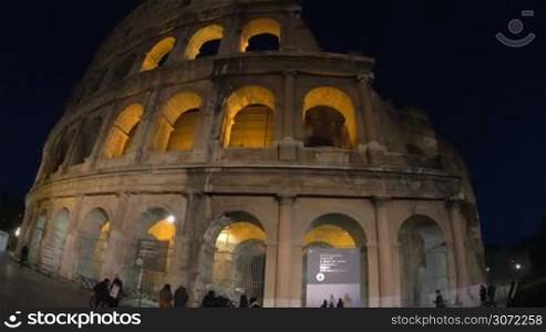 Dolly and wide angle shot of illuminated Coliseum at night. Ancient amphitheatre in Rome