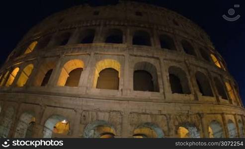 Dolly and wide angle shot of the most famous Italian landmark. Low angle view of illuminated Coliseum at night