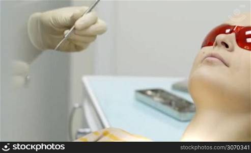 Dolly close-up shot of a woman patient being under dental examination in clinic