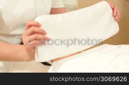 Dolly shot of a relaxed woman getting face therapy with warm towel at beauty salon
