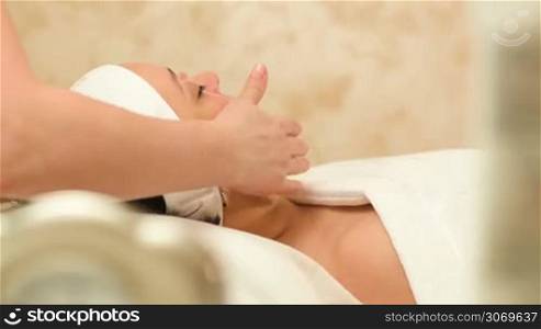 Dolly shot of a woman getting professional facial massage by therapist at beauty spa
