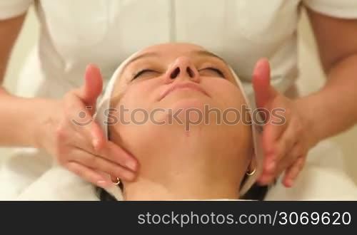 Dolly shot of a woman relaxing during facial massage ar beauty treatment salon