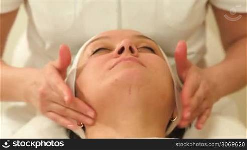 Dolly shot of a woman relaxing during facial massage ar beauty treatment salon