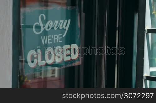 Dolly shot of a woman turning over shop-sign. Vintage style open sign inviting customers to come in
