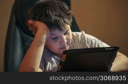 Dolly shot of boy using tablet PC sitting at the table