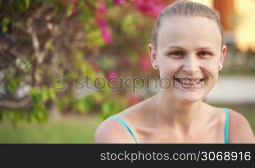 Dolly shot of pretty happy woman. Young female with kind and charming smile on summer background