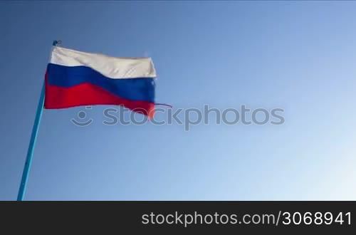 Dolly shot of Russian and German flags waving in the breeze against clear blue sky