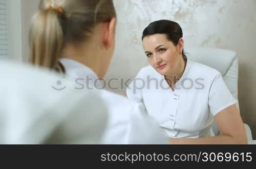 Dolly shot of woman cosmeticians talking. Young cosmetician consulting an experienced colleague