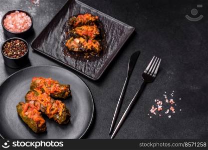 Dolma, stuffed grape leaves with rice and meat on a dark background. Caucasian and Turkish cuisine. Dolma, stuffed grape leaves with rice and meat on a dark background