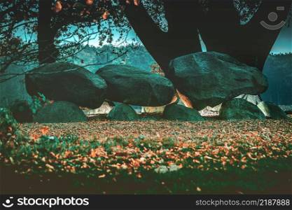 Dolmen in the Dutch province of Drenthe with a background of oak trees. A dolmen or in Dutch a Hunebed is construction work from the new stone age.. Spooky Ancient Dolmen or Hunebed Megalithic tomb from the ice age