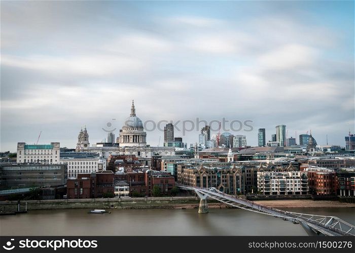Dome of St. Pauls Cathedral and modern skyscrapers of The City of London as seen from the South shore of the river Thames on a cloudy Summer day. Long exposure.