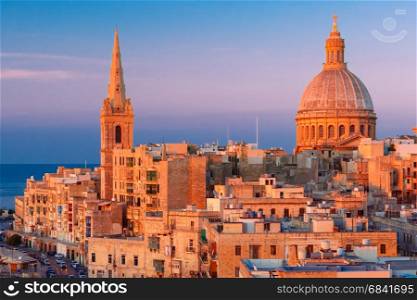 Domes and roofs at sunset, Valletta , Malta. View from above of the domes of churches and roofs at beautiful sunset with churches of Our Lady of Mount Carmel and St. Paul&rsquo;s Anglican Pro-Cathedral, Valletta, Capital city of Malta