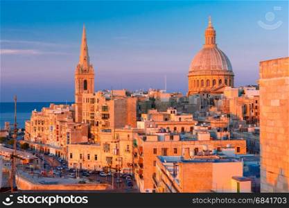 Domes and roofs at sunset, Valletta , Malta. View from above of the domes of churches and roofs at beautiful sunset with churches of Our Lady of Mount Carmel and St. Paul&rsquo;s Anglican Pro-Cathedral, Valletta, Capital city of Malta