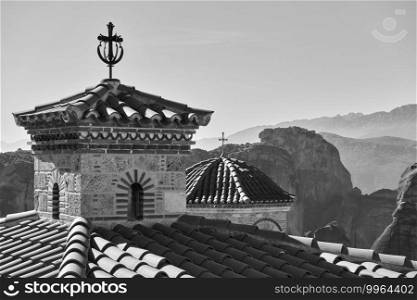 Domes with crosses of Varlaam orthodox monastery and Meteora rocks in the background, Greece. Black and white greek landscape