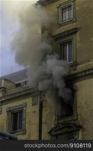 Domestic apartment fire with smoke billowing from window. Garibaldi Square, Naples, Italy, portrait