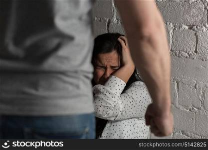 domestic violence, abuse and people concept - man beating helpless scared woman. unhappy woman suffering from domestic violence