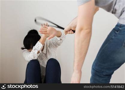 domestic violence, abuse and people concept - man beating helpless scared woman with belt. unhappy woman suffering from domestic violence