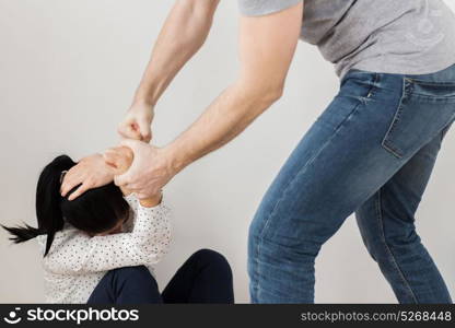 domestic violence, abuse and people concept - man beating helpless woman at home. unhappy woman suffering from domestic violence