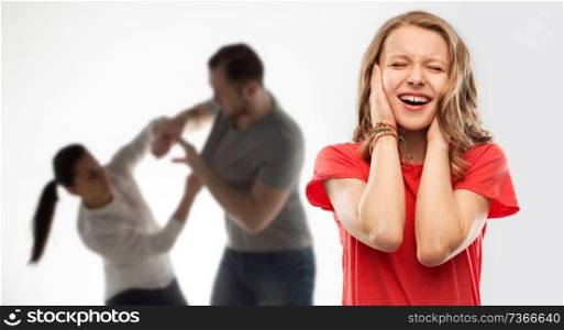 domestic violence, assault and social issue concept - unhappy stressed teenage girl covering her ears when her mother and father having fight background. girl covering ears over her parents having fight