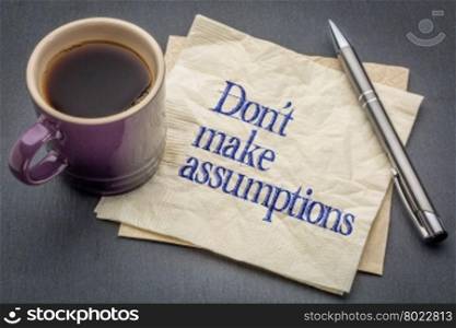 Don not make assumption advice or reminder - handwriting on a napkin with cup of coffee against gray slate stone background