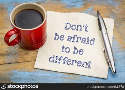 Don't be afraid to be different - inspirational handwriting on a napkin with a cup of coffee