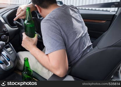 Don't Drink for Drive concept, Young Drunk man drinking bottle of beer or alcohol during driving the car dangerously.