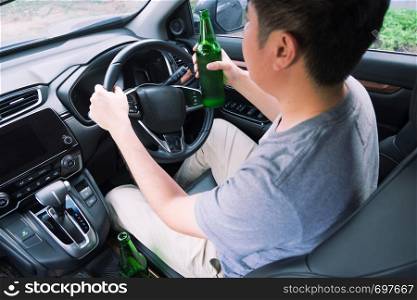 Don't Drink for Drive concept, Young Drunk man drinking bottle of beer or alcohol during driving the car dangerously.