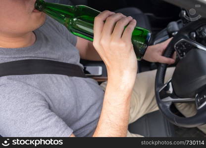 Don't Drink for Drive concept, Young Drunk man drinking bottle of beer or alcohol during driving the car dangerously.