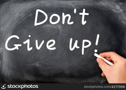Don&rsquo;t give up written on a blackboard,with a hand holding chalk