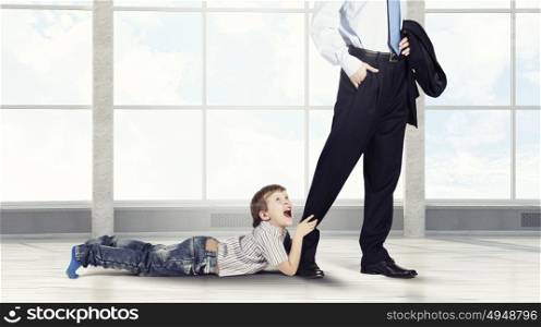 Don&rsquo;t go away daddy. Close up of legs of busy father going to job and his son praying him to stay
