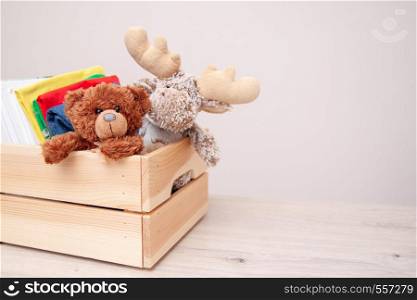 Donation concept. Donate box with kids clothes, books, school supplies and toys. TTeddy bear and moose toy. Copyspace for text. Donation concept. Donate box with kids clothes, books, school supplies and toys. Teddy bear and moose toy. Copyspace for text.