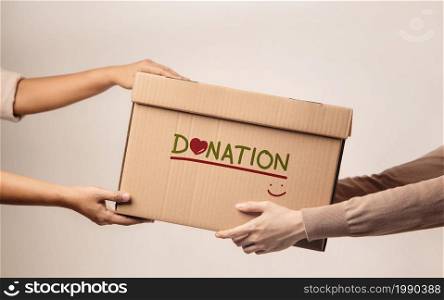 Donation Concept. The Volunteer Giving a Donate Box to the Recipient. Standing against the Walll