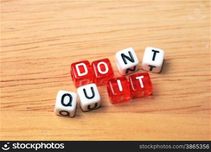 Dont Quit Do It written on red and white dices on wooden background