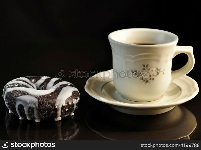 donut and cup of coffee on black background