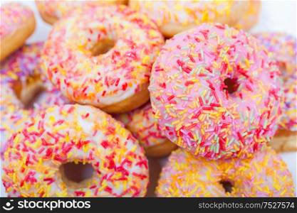 Donuts or doughnuts with colorful frosting or icing and sprinkles photographed on a white background