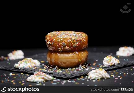 donuts with strawberry syrup and coloured topping with cream on a black background
