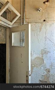 Door frame and peeling paint wall in abandoned house interior.