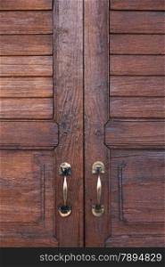 door handle. Brown wooden door. The door handle is aluminum.