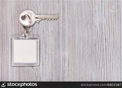 door key with white blank key chain on wooden background