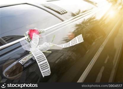 Door of black wedding car with flower and ribbon