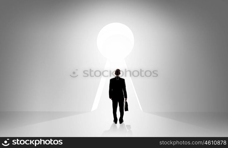 Door to new opportunities. Back view of businessman standing in keyhole doorway