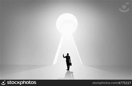 Door to new opportunities. Back view of businessman standing in keyhole doorway