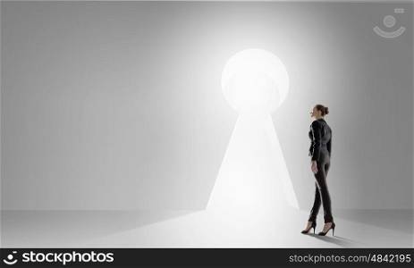 Door to new opportunities. Back view of businesswoman standing in keyhole doorway