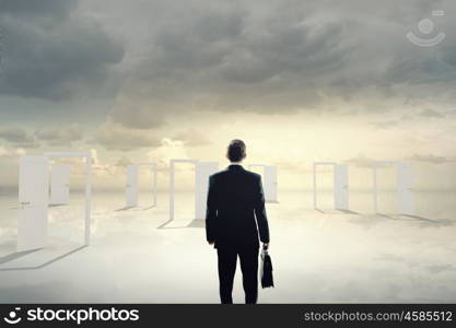 Door to new opportunity. Businessman standing in front of opened doors and making decision