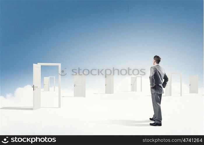Door to new opportunity. Businessman standing in front of opened doors and making decision