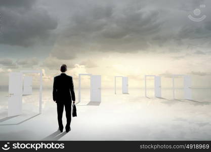 Door to new opportunity. Businessman standing in front of opened doors and making decision