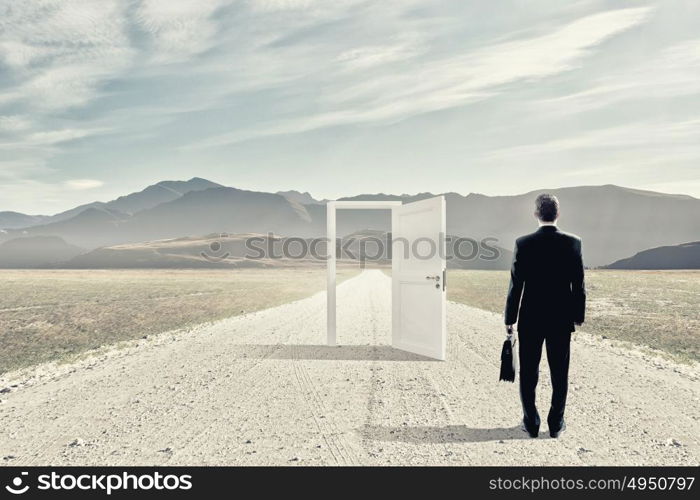 Door to new opportunity. Businessman standing in front of opened doors and making decision