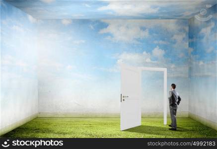 Door to new opportunity. Businessman standing in front of opened doors and making decision