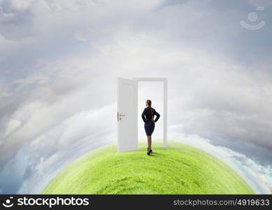 Door to new opportunity. Businesswoman standing in front of opened doors and making decision