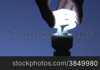 Doppelwendel-Energiesparlampe eindrehen, blauer Hintergrund
